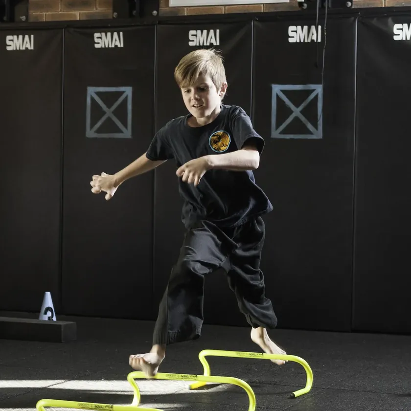 A Little Dragons student leaping agility hurdles