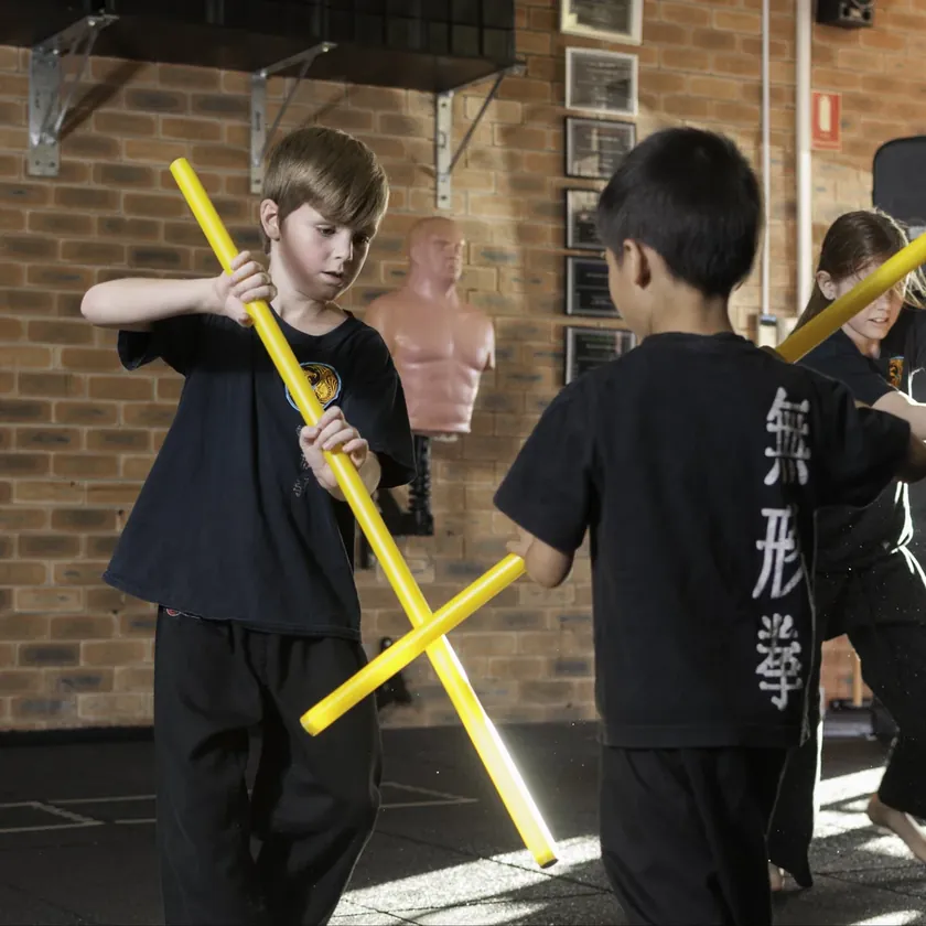 Two Little Dragons students crossing training poles