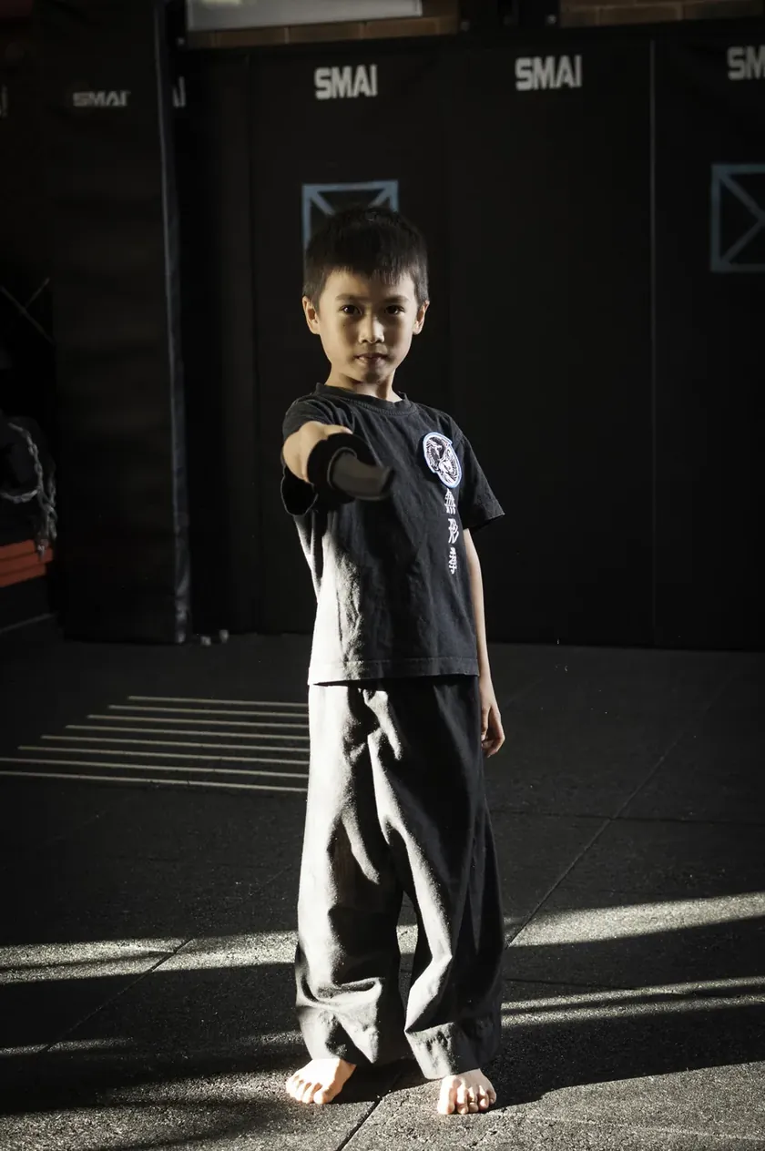 A young Little Dragons student standing proud with a training sword