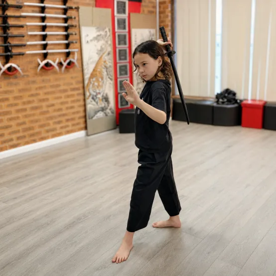 Little Dragons student in a sword-and-palm stance in the training hall